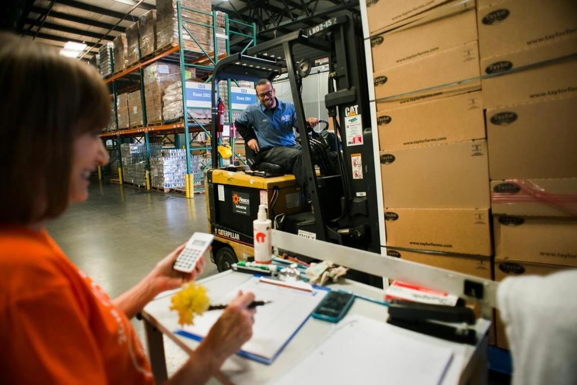 FILE -- Sacramento Food Bank & Family Services volunteer, Judy Clark, left, smiles at Warehouse Assistant, Aaron Smith as he places places food onto a scale to be weighed during a Guinness Book of World Record attempt in progress at the Sacramento Food Bank & Family Service's distribution center on Wednesday Sept. 7, 2016.
