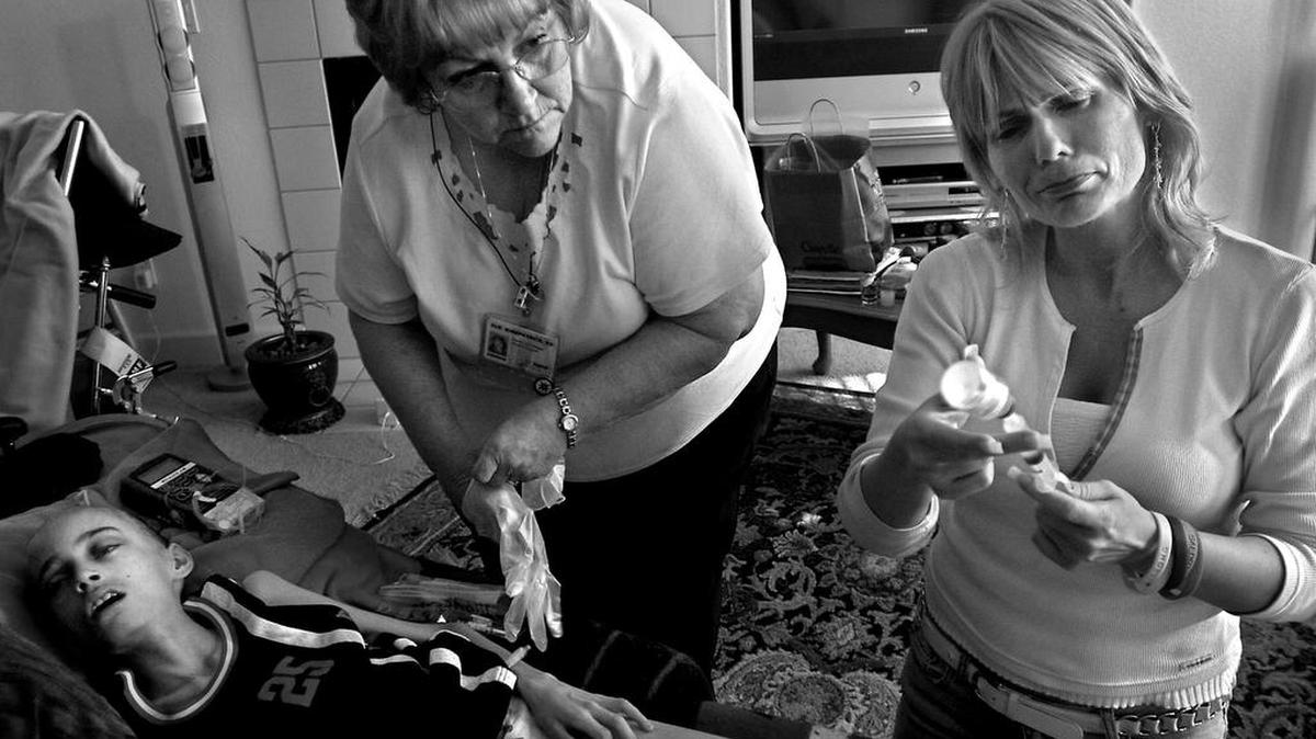 Cyndie French fights her emotions May 10, 2006, as she prepares to flush out Derek's catheter with saline solution before hospice nurse Sue Kirkpatrick, left, administers a sedative that will give the 11-year-old a peaceful death. "I know in my heart I've done everything I can," Cyndie says.