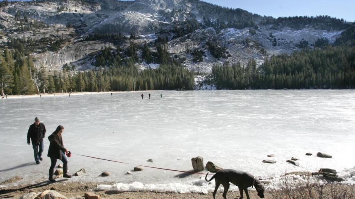 A couple walk their dog along the frozen Tenaya Lake along with about 100 others on New Year's day, 2012. The weather was fair, the skies blue and in a rare event Tioga Pass Road was open. In 2017, the Tioga Pass Road is set to reopen on Thursday morning, weather permitting.