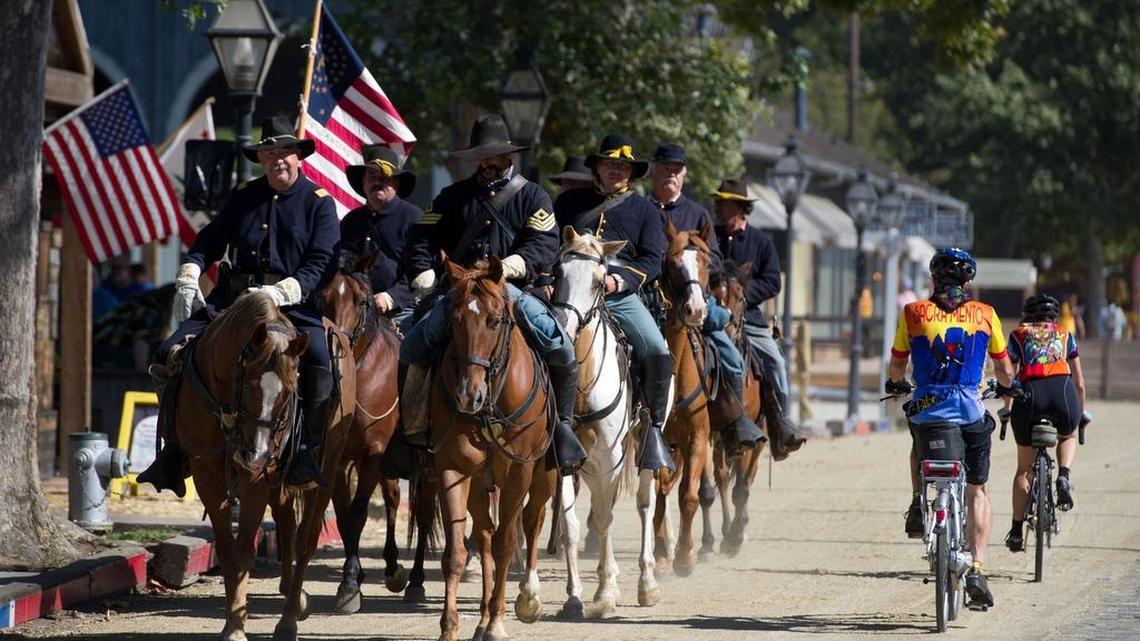 
Members of Company F, 2nd Calvary, locally known as the Sacramento Rangers during the 1800s, are passed by bike riders on Front Street in September 2011. 
