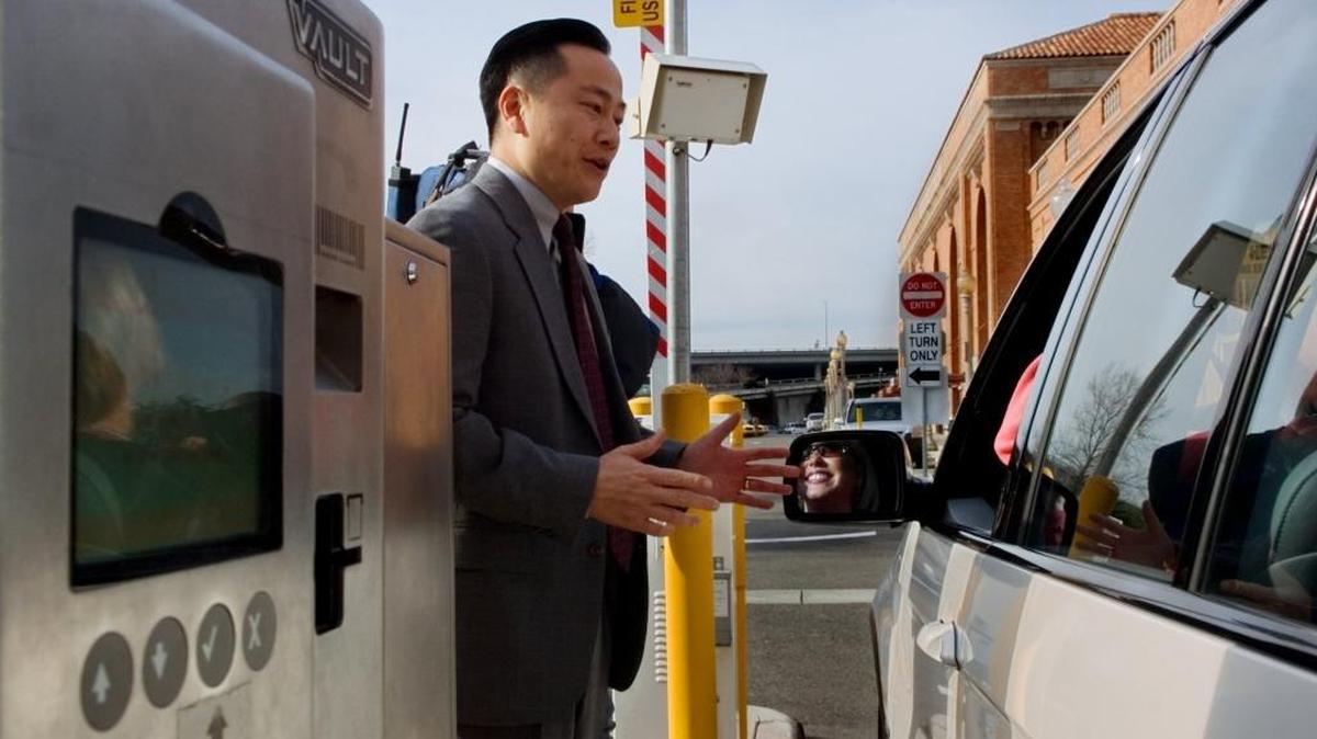 Then-Sacramento parking manager Howard Chan, left, greets a motorist at the entrance to the parking lot at the Amtrak rail station in Sacramento on Friday December 29, 2006. Chan is Sacramento’s new interim city manager.