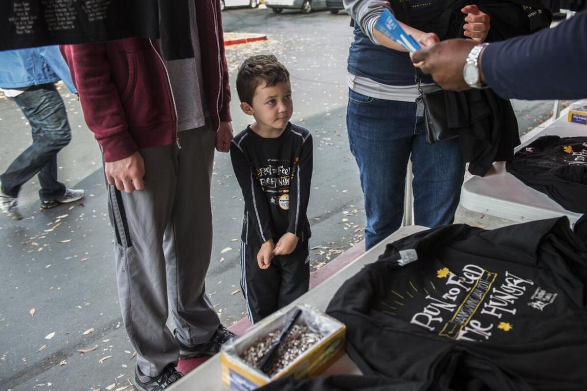 Charlie Daugherty, 4 1/2, center wears a t-shirt from another Run for the Hungry race as he waits for his new one for tomorrow at REI in Sacramento on Wednesday, Nov. 22, 2017. He was there with his brother Jackson Grogan, 18, and mom Lori Daughterty, who he will run with.