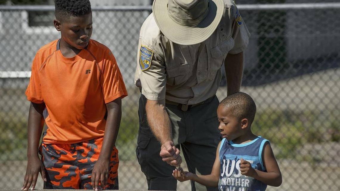 Devin Enoch, 12, left, watches as California Fish and Wildlife Scientific Aid Brian Gilmore gives some fish food to Jaylin Livington, 5, at the Nimbus Fish Hatchery in Rancho Cordova on Tuesday. The American River Parkway Foundation is focusing this summer on getting underprivileged urban children out to the river to hike, bike and meditate.