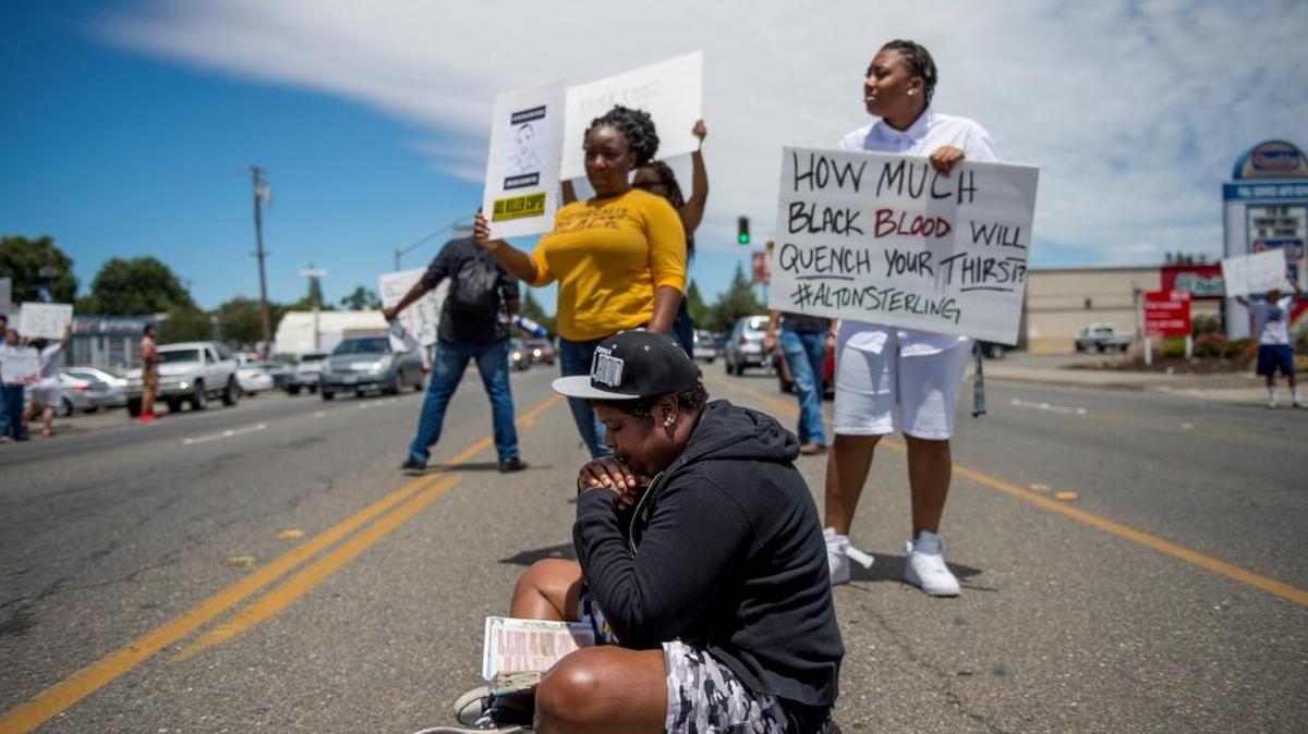 Jackie Turner prays while reading the bible in the middle of Fair Oaks Blvd at a Black Lives Matter demonstration on Saturday, July 9, 2016, in Carmichael, Calif. "In the midst of what people are going through repaying evil for evil is not the way to go about this," she said.