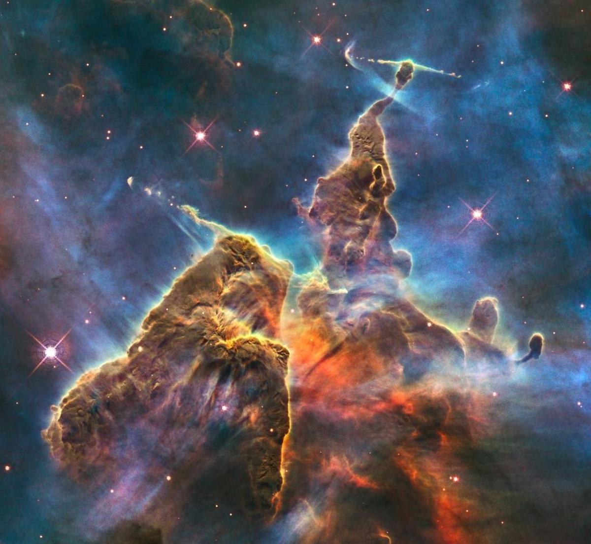 This February 2010 image made by the Hubble Space Telescope shows a three-light-year-tall pillar of gas and dust in the Carina Nebula which is being eaten away by the light from nearby bright stars. Inside, infant stars fire off jets of gas that can be seen streaming from towering peaks. The stellar nursery is located 7,500 light-years away in the southern constellation of Carina. The colors in this composite image correspond to the glow of oxygen (blue), hydrogen and nitrogen (green), and sulphur (red).