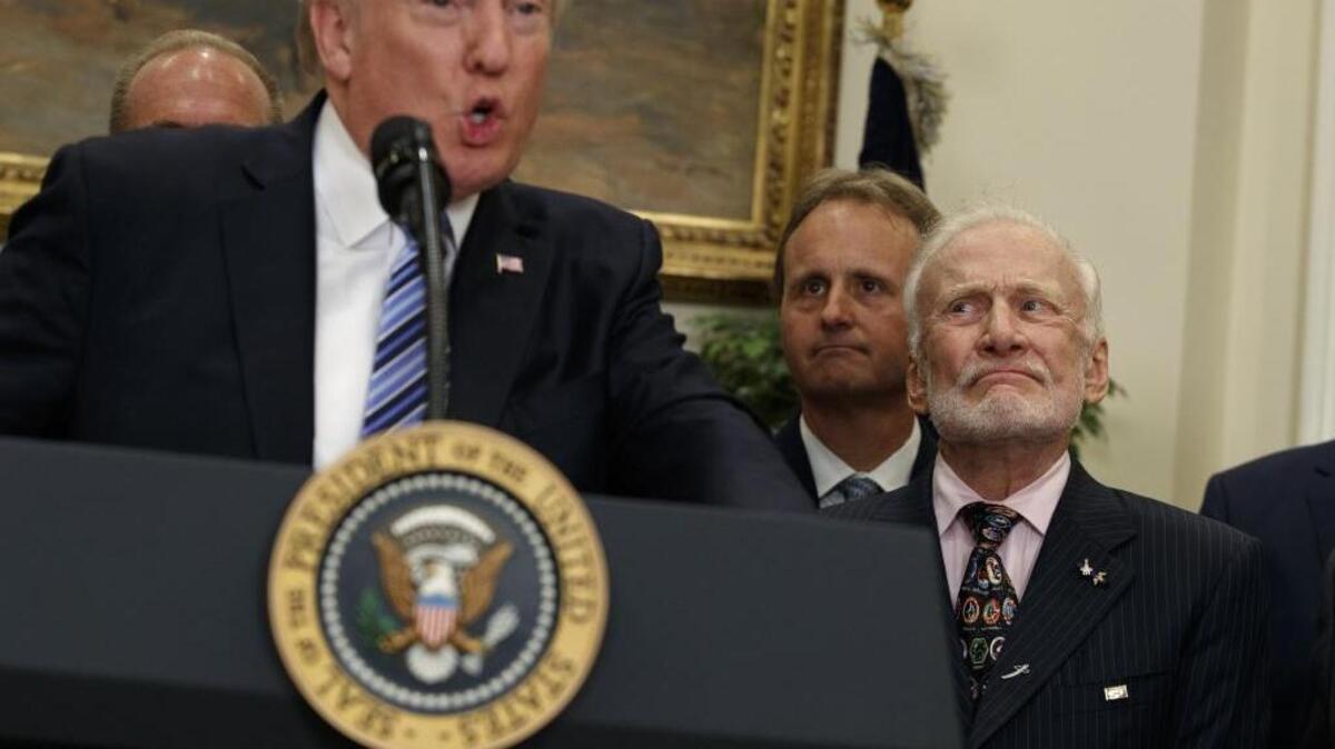 Former astronaut Buzz Aldrin listens at right as President Donald Trump speaks before signing an executive order to establish a National Space Council on Friday in the Roosevelt Room of the White House in Washington.