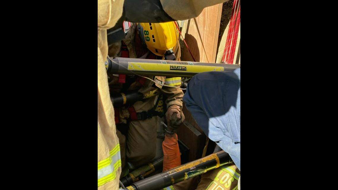 A construction worker buried in a trench for hours grasps a Los Angeles firefighter’s hand.