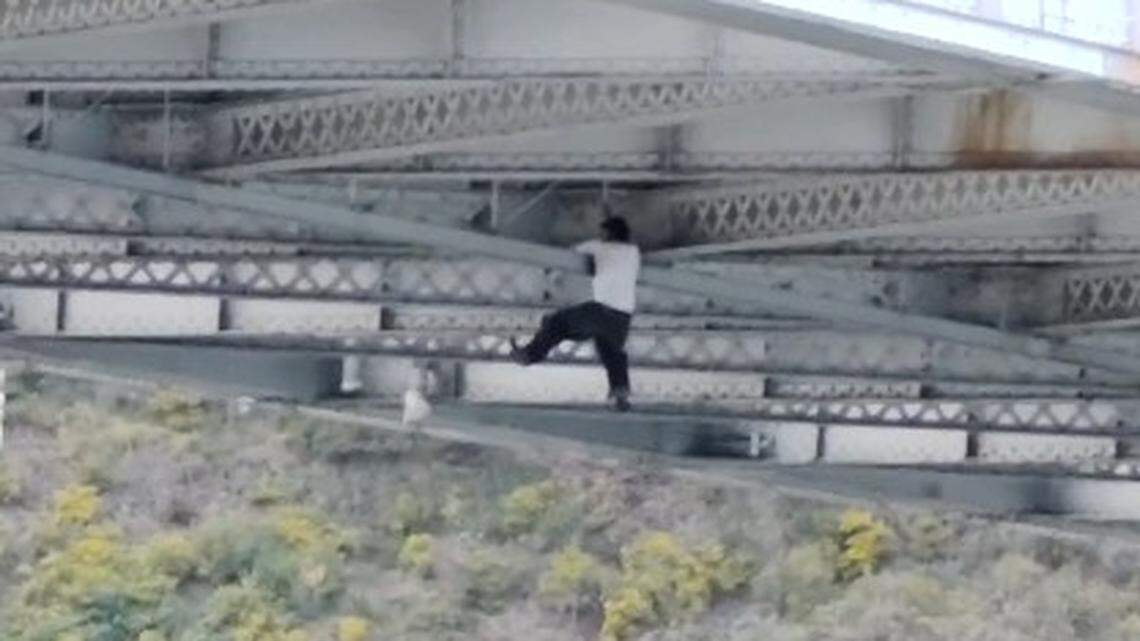 A man dangles from beneath the San Francisco-Oakland Bay Bridge after trying to escape police, a video shows.