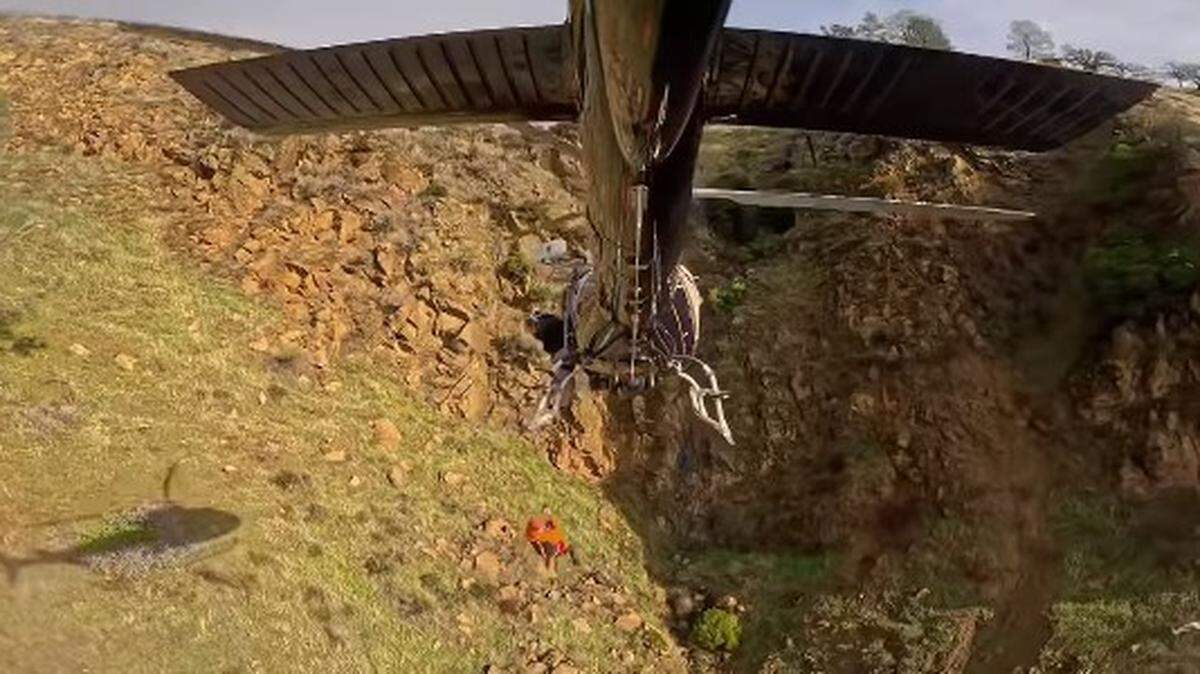 A hiker and rescuer, both injured, spent a stormy night before they could be airlifted to safety, California officials say.