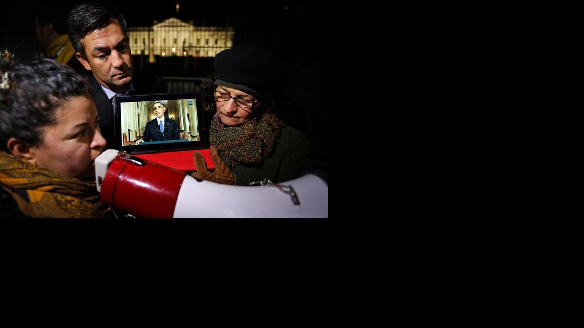 Rosa Lozano, from Washington, left, translates President Obama’s speech into Spanish as Lita Trejo, from El Salvador, and Texas Democratic State Rep. Ramon Romero, listen to the address on a tablet in front of the White House on Thursday night.
