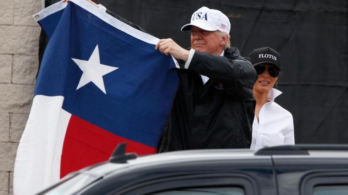 President Donald Trump, accompanied by first lady Melania Trump, holds up a Texas flag after speaking with supporters Tuesday in Corpus Christi, Texas. The president is pledging $1 million of his personal money to Harvey relief efforts.