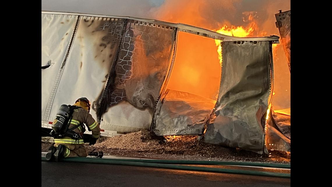 Smoke billows from the truck, surrounded by chickpeas scattered on the floor, as firefighters battle the blaze.