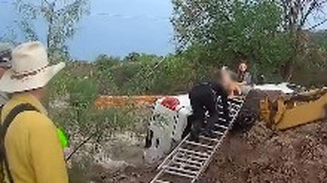 The officer found a woman, child and dog trapped on top of the wrecked vehicle in the rushing water, police say.