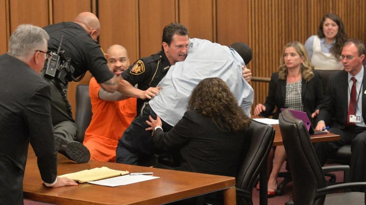 A court officer tackles the father of one of three victims of Ohio serial killer Michael Madison, left, who leaped over a table to attack the defendant in court just minutes after the judge pronounced a death sentence in Cuyahoga County Common Pleas Court Thursday, June 2, 2016, in Cleveland. Van Terry, the father of victim Shirellda Terry, had walked to the front of the courtroom to give a victim-impact statement when he turned, paused and lunged toward Madison, who gave him a malicious smile.