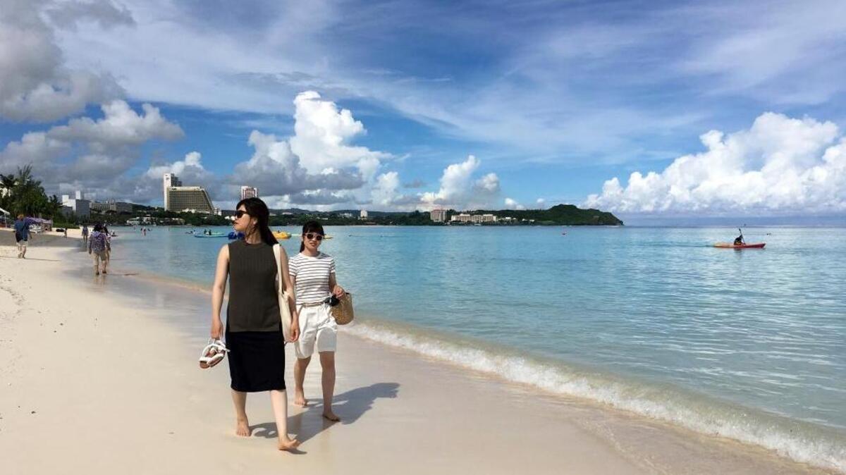 Tourists walk the beach in Tumon, Guam on Thursday. The small U.S. territory of Guam has become a focal point after North Korea's army threatened to use ballistic missiles to create an "enveloping fire" around the island. The exclamation came after President Donald Trump warned Pyongyang of "fire and fury like the world has never seen."