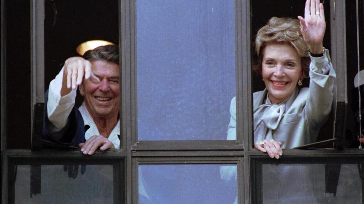 In this July 18, 1985, file photo, President Ronald Reagan and his wife, Nancy, wave from windows of his hospital room at the Navy Medical Center in Bethesda, Md. The former first lady has died at 94, The Associated Press confirmed Sunday, March 6, 2016.