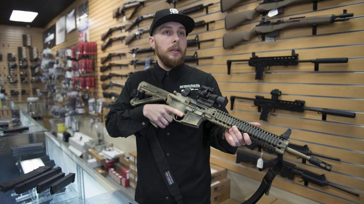 Nate Woodward, manager at Sacramento Black Rifle, holds an AR-15-style rifle, which is now illegal to sell in California.