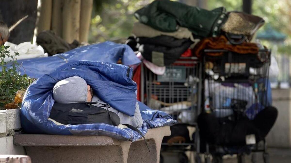 A homeless man rests inside a sleeping bag downtown Los Angeles, on Friday, Nov. 27, 2015.