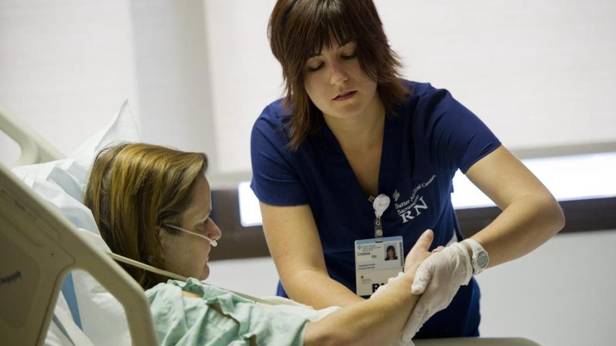 Chelsea Hallford, a newly hired nurse at Sutter Memorial, checks in on patient, Britta Sharpe, on the cardiac ward on Sept. 12, 2014. Nurses and other health care workers face an increased risk of violence on the job.