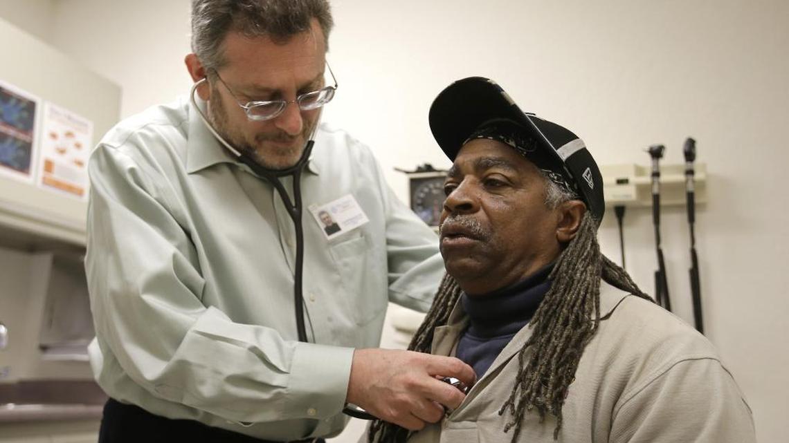 In this photo taken Thursday, Feb. 18, 2016 Doctor Leonid Basovich, left, examines Medi-Cal patient Michael Epps, at the WellSpace Health clinic in Sacramento. California lawmakers recently approved an expanded health plan tax to help pay for Medi-Cal. The state this week formally asked the federal government to sign off on its proposal.