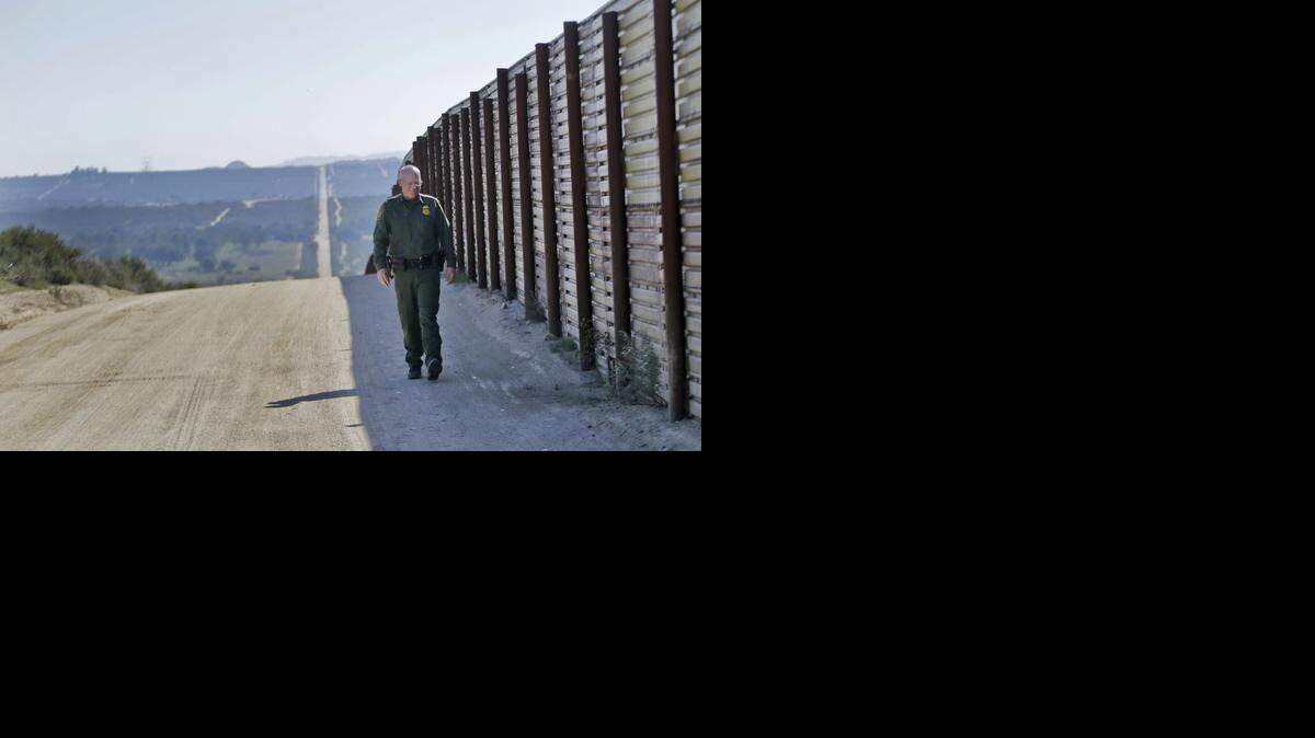
In this Monday, March 25, 2013 photo, Border Patrol agent Richard Gordon walks the border fence in the Boulevard area east of San Diego looking for signs that reveal movement of illegal immigrants in the rugged, mountainous terrain in Boulevard, Calif.
