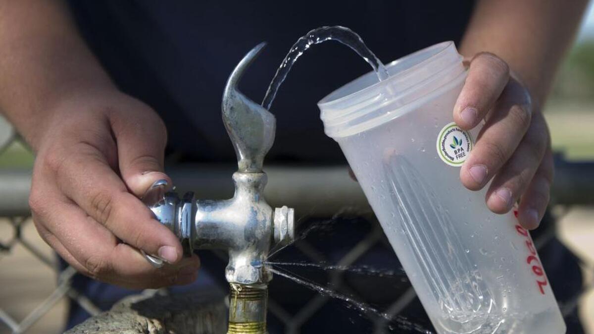 
A member of the Washington Union High school football team in Easton fills his water container during football training in May. 
