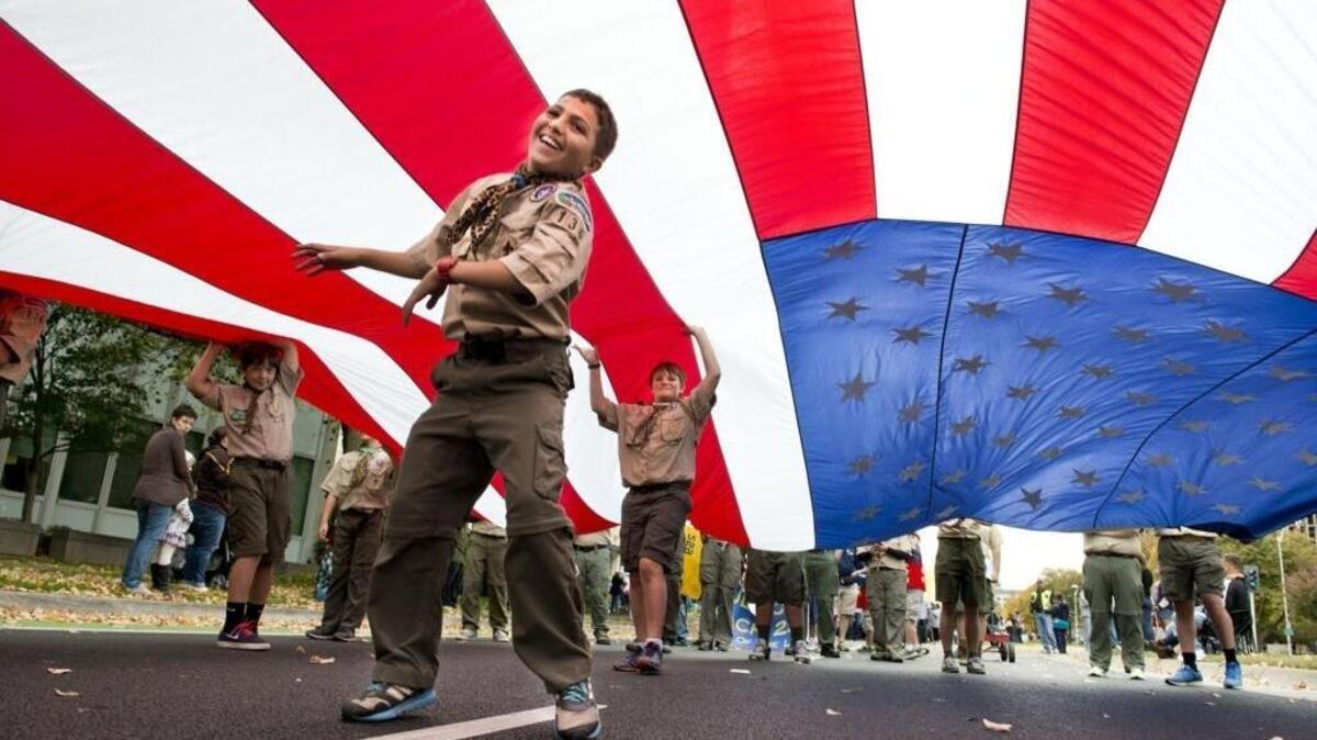 Santiago Ortiz, 11, left, and and Spencer Tacherra, 14, both members of the Boy Scout Troop 136 keep a huge flag from touching the ground while other members line the perimeter while they walk down Capitol Mall during the Fourth Annual Veterans Day Parade on Tuesday, Nov. 11, 2014 in Sacramento.
