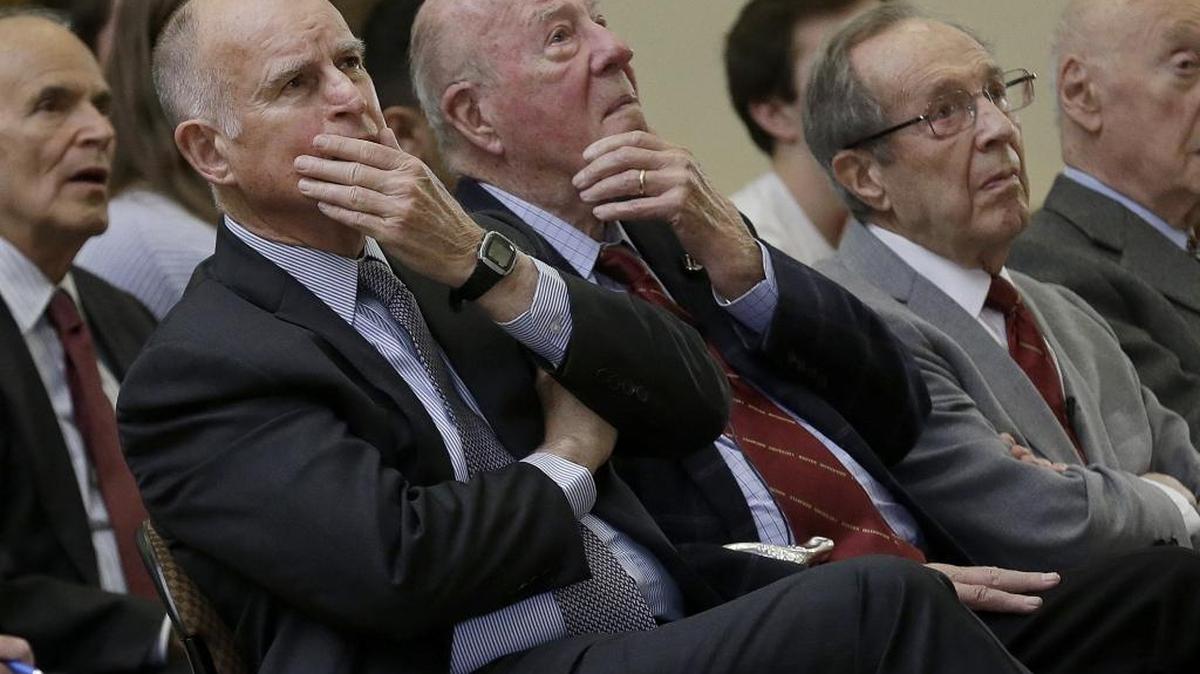 California Gov. Jerry Brown, from left, former U.S. Secretary of State George Shultz and former U.S. Secretary of Defense William Perry listen to speakers on a video screen before the unveiling of the “Doomsday Clock,” which measures the likelihood of a global cataclysm, at Stanford University in Stanford, Calif., Tuesday, Jan. 26, 2016.
