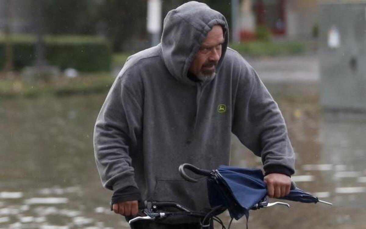 William Hudnell rides his bike through the water on Lindberg Lane in Petaluma, Calif., after heavy rains caused flooding on Wednesday, Dec. 3, 2014.