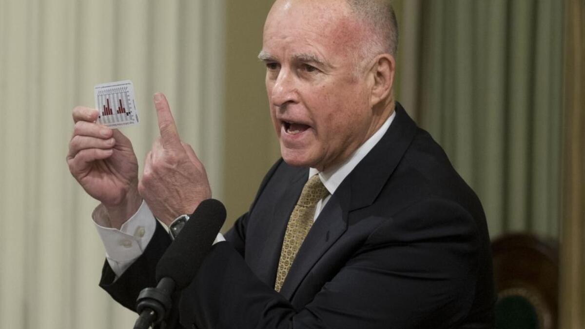 Gov. Jerry Brown shows a card with the state budget as he delivers the 2014 State of the State address to a joint session of the Legislature on Jan. 22, 2014 in Sacramento.