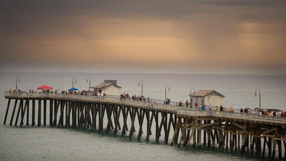 
As storm clouds loom in the distance, lifeguards advise people to leave the pier and beach during the Ocean Festival in San Clemente, Calif.
