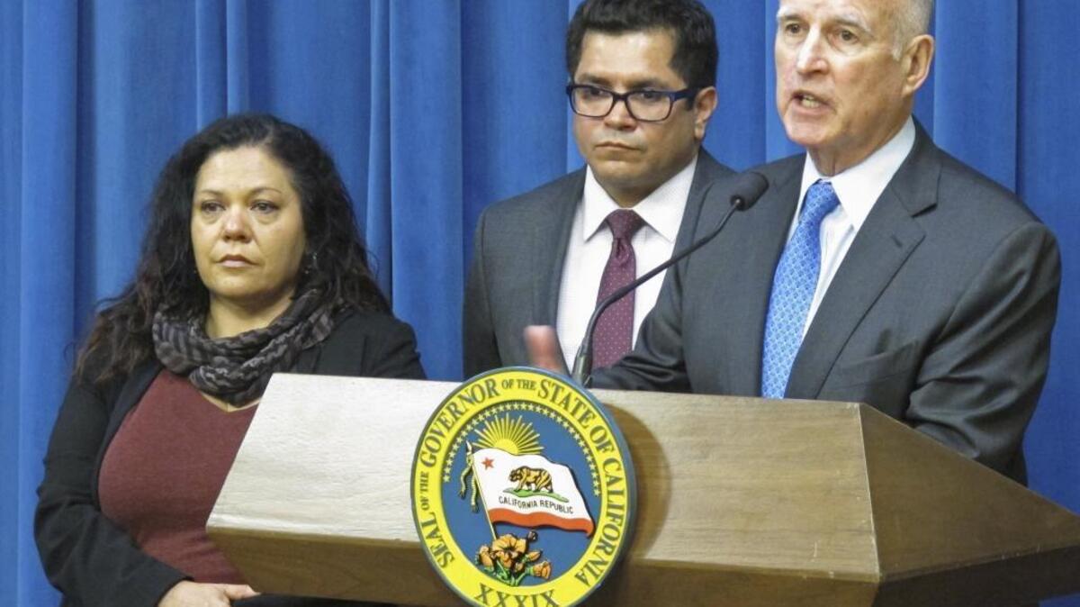 Gov. Jerry Brown, right, speaks in his office on Monday after signing into law a bill increasing the amount of income Californians can receive during paid family leave.