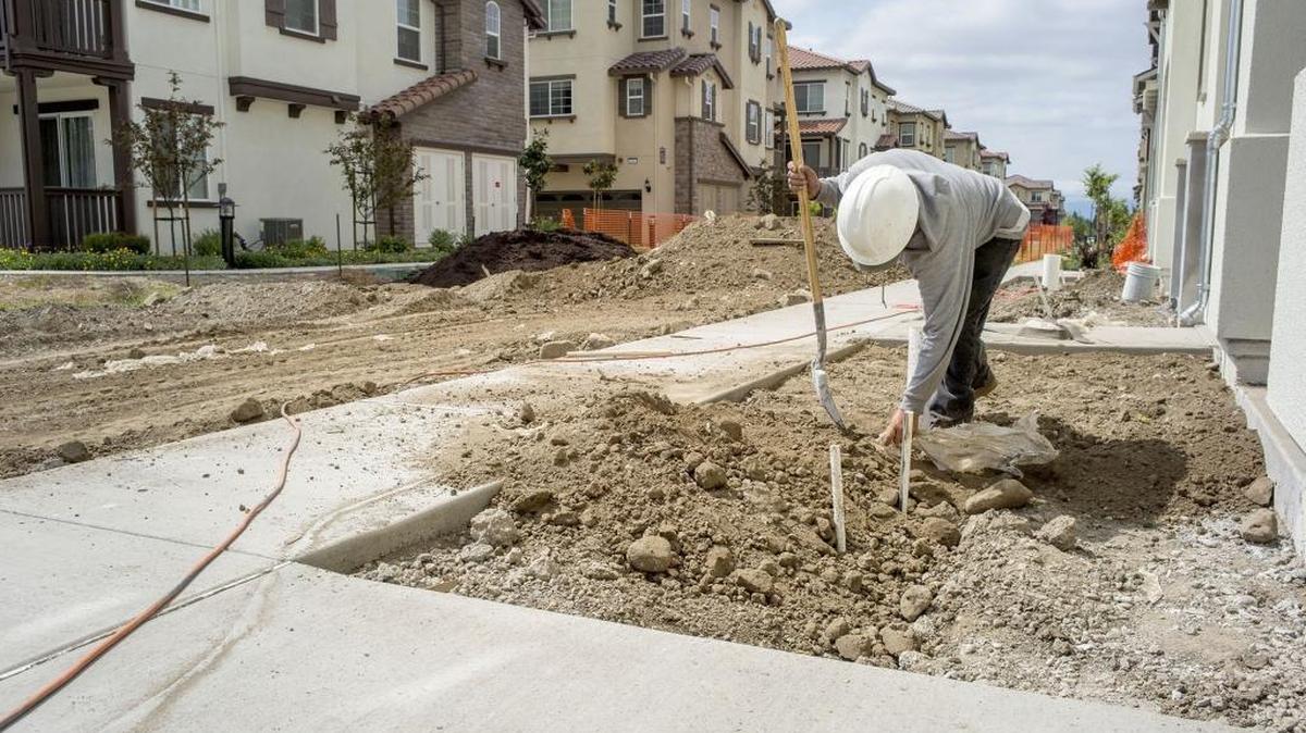 A contractor shovels dirt in front of townhouse under construction at the Pulte Homes Inc. Pepper Lane development in San Jose, California. Purchases of new homes slumped more than forecast in March from a seven-year high, a sign progress in the industry will be halting.