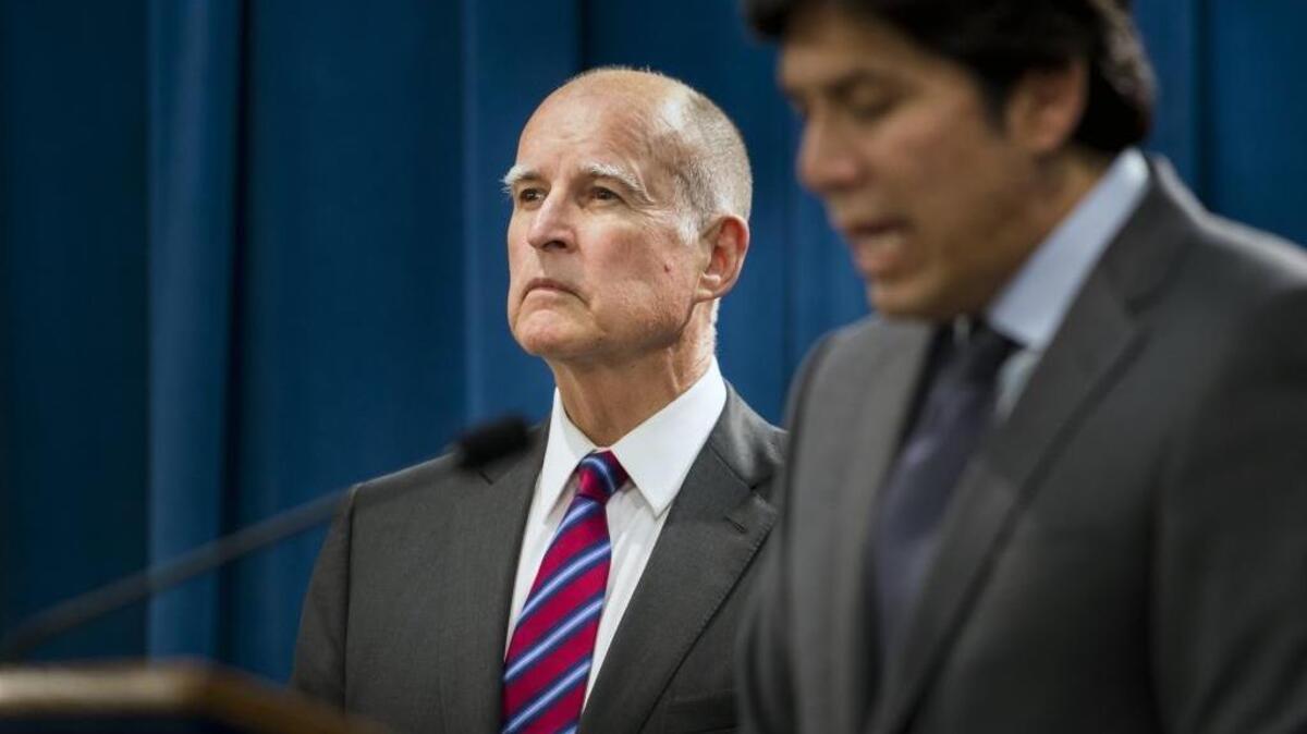 
Gov. Jerry Brown, left, listens to Senate President Pro Tem Kevin de León as he announces they will abandon efforts this year to require a 50 percent reduction in petroleum use by motor vehicles on Sept. 9, 2015.
