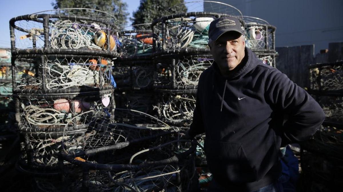 Fisherman Jim Anderson stands surrounded by crab pots in a storage yard in Half Moon Bay, Calif. California has delayed the Nov. 15 start of its commercial crab season after finding dangerous levels of a toxin in crabs.