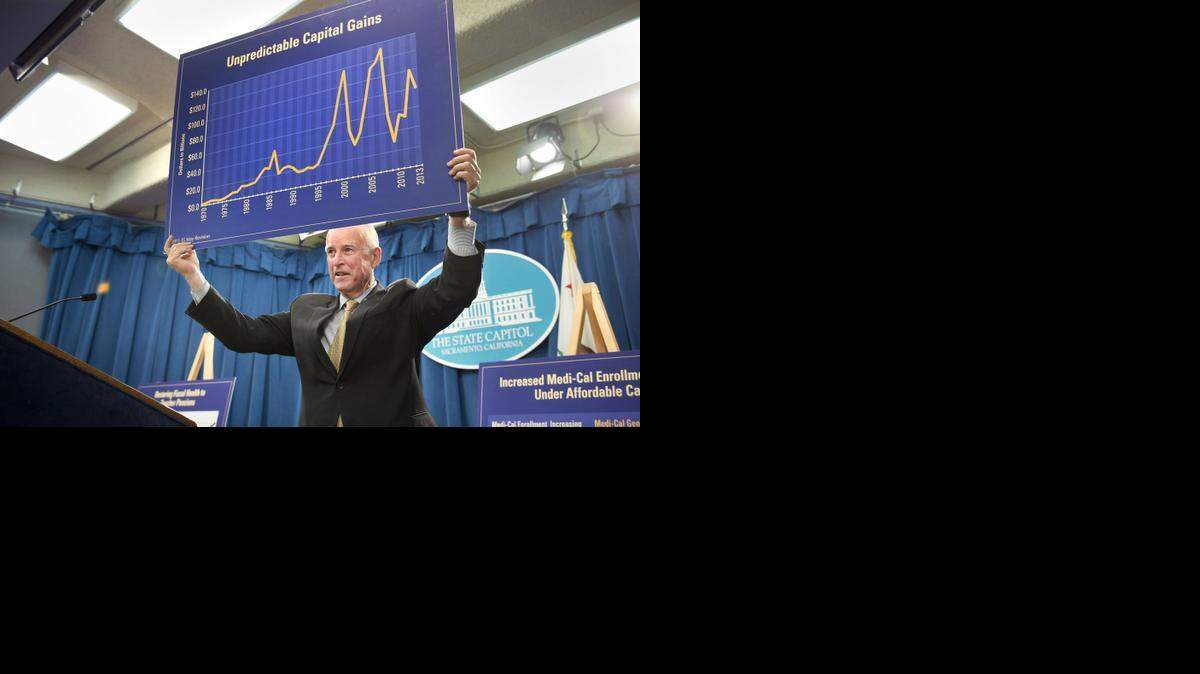 
California Gov. Jerry Brown holds up poster boards with graphic information regarding revisions to his budget, specifically related to his projected increase in spending on health care and teacher pensions, during a news conference at the state Capitol on Tuesday, May 13, 2014, in Sacramento.
