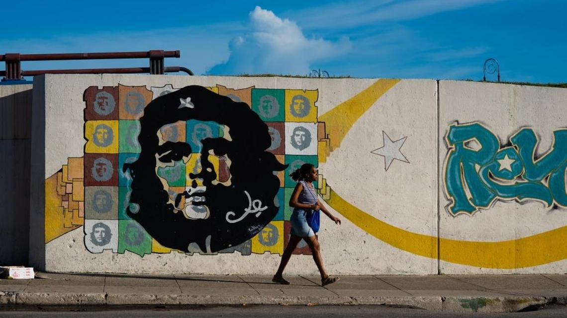 A woman walks past a mural in Old Havana, Cuba on the morning of August 16, 2015.