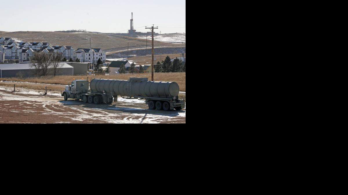
FILE -- In this Feb. 26, 2014 photo, an oil truck sits in a dirt lot near a new housing development in Watford City, N.D. The housing development is part of the town's growth explosion from the Bakken oil boom. The state has the country’s lowest unemployment.
