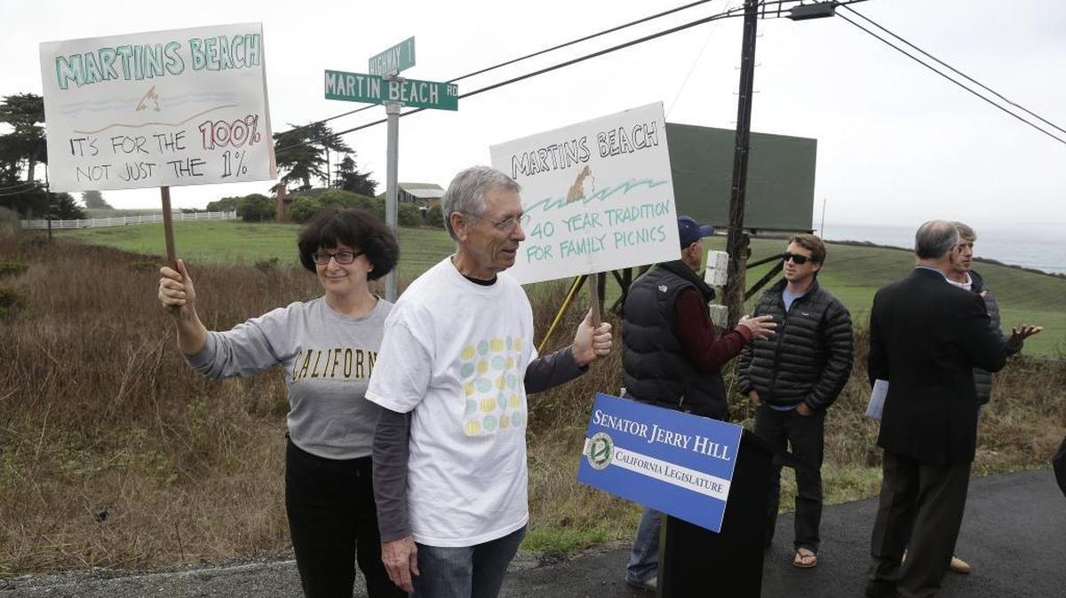 File - In this Feb. 10, 2014, file photo, Julie Graves, left, of Albany, Calif., and Chris Adams, second from left, of Berkeley, Calif., hold up signs in support of a beach access bill that Democratic state Sen. Jerry Hill introduced near Martin's Beach in Half Moon Bay, Calif. California's Coastal Commission is asking the public to document its use of Martin's Beach after billionaire landowner Vinod Khosla closed the only access road to it.