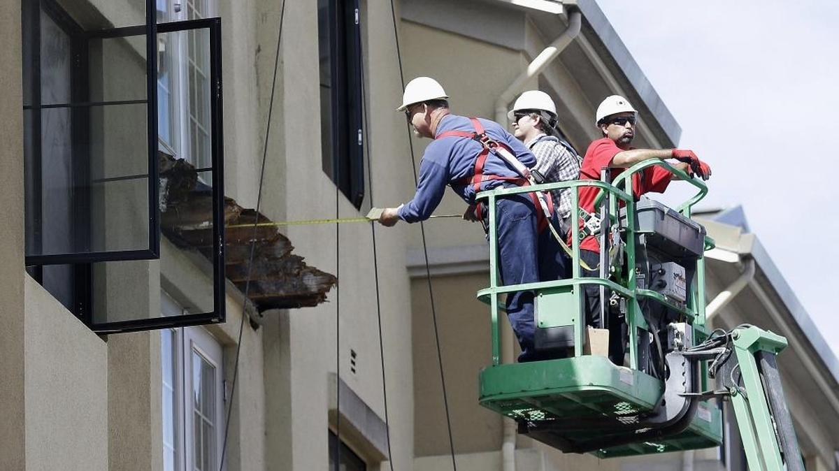 A worker measures near the remaining wood of a Berkeley apartment building balcony that collapsed on June 16, 2015, killing six college students and injuring several others.