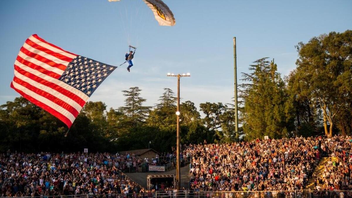 A skydiver parachutes an American flag into the Folsom Pro Rodeo on July 2015 at Dan Russell Rodeo Arena in Folsom. A skydiver participating in the rodeo’s traditional flag presentation Thursday was uninjured except for a cut to his lip after landing outside the stadium when the flag appeared to snag on a nearby tree. He is expected to jump again for the soldout crowd Friday.