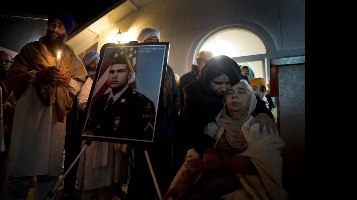 
Kulbinder Kaur comforts her mother Sukhwinder Kaur as she sits next to a photograph of her son Parminder Singh Shergill, an Iraq war veteran with Post Traumatic Stress Syndrome shot by police after they said he lunged at officers with a knife.
