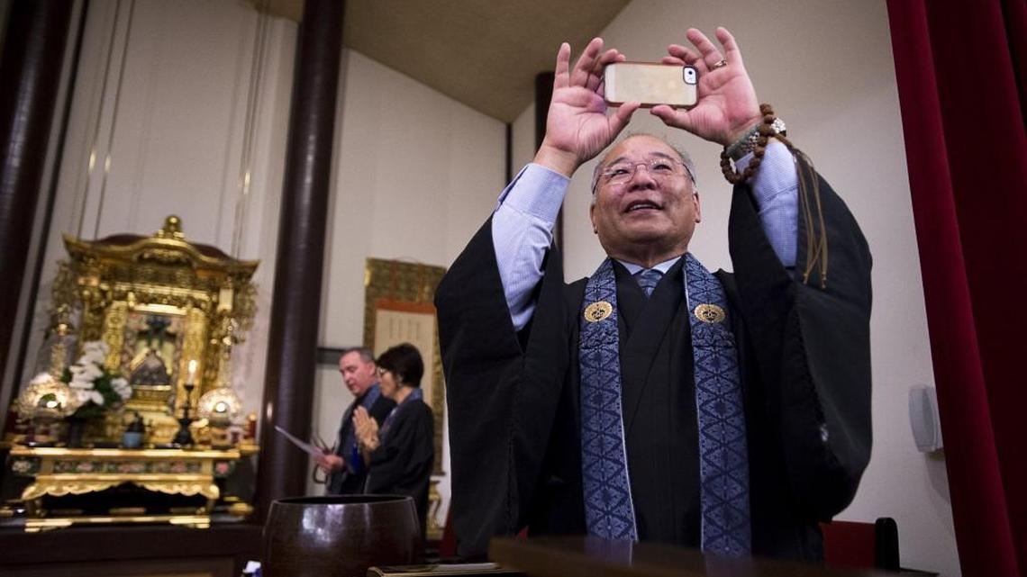 Rev. Bob Oshita videos his congregation during a farewell song at his final service after 32 years at the Buddhist Church of Sacramento on May 29, 2016.