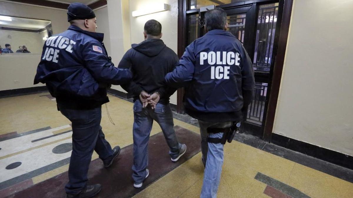 U.S. Immigration and Customs Enforcement officers escort an arrestee from an apartment building in the Bronx during a series of early-morning raids on March 3, 2015.