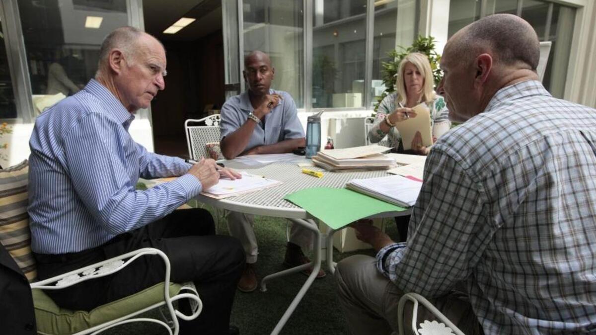 
 Gov. Jerry Brown, left, signs bills with his staff in 2012.
