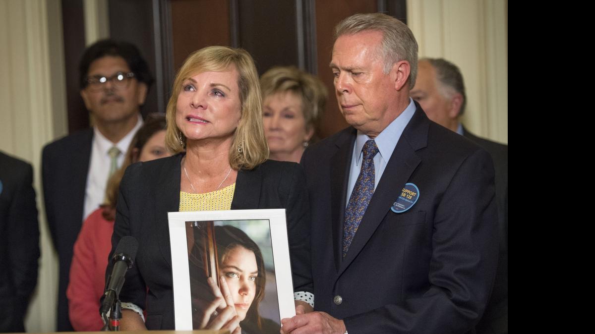 
Deborah Ziegler holds a photo of her daughter, Brittany Maynard, with her husband Gary Holmes after the California Senate passed SB 128 on June 4.
