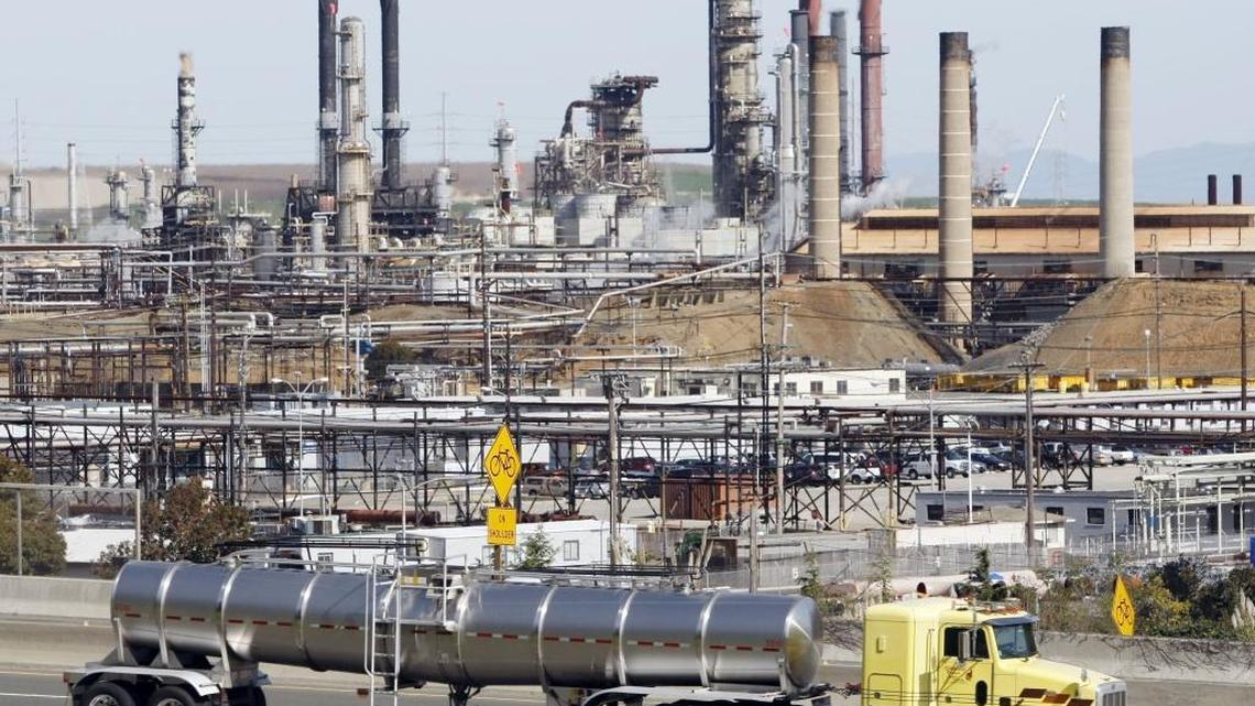 This 2010 file photo shows a tanker truck passing the Chevron oil refinery in Richmond, Calif. The refinery is one of many California sources of carbon dioxide emissions covered by the state’s cap-and-trade system of pollution control.