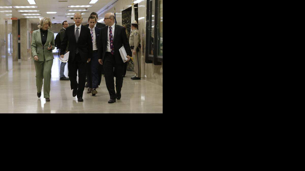 
Gov. Jerry Brown, center, talks with adviser Nancy McFadden, left, and Finance Director Michael Cohen, right, as he walks to a news conference to unveil his proposed 2015-16 state budget plan in Sacramento, Calif., Friday, Jan. 9, 2015.

