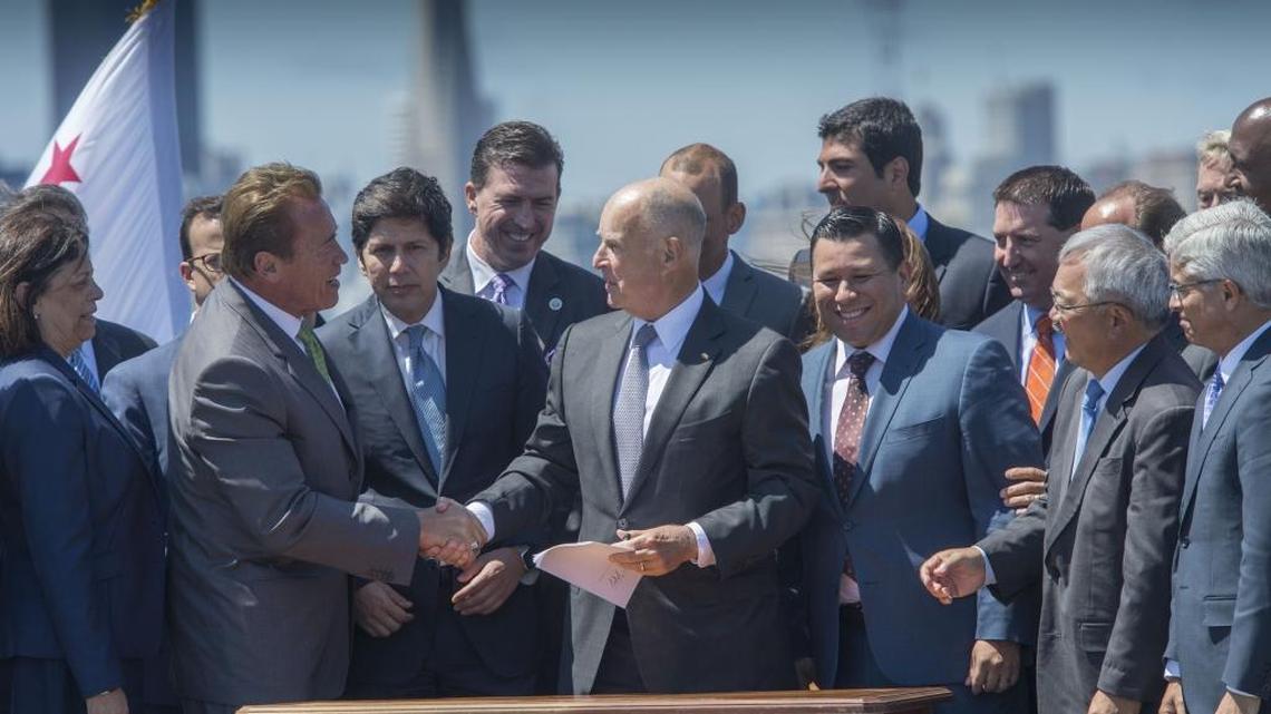 Gov. Jerry Brown, accompanied by his predecessor, Republican former Gov. Arnold Schwarzenegger, after Brown signed a bill extending cap and trade climate auctions until 2030, on July 25, 2017, in Treasure Island.