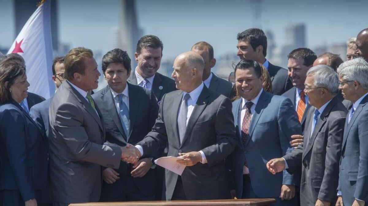 Gov. Jerry Brown, accompanied by his predecessor, Republican former Gov. Arnold Schwarzenegger, after Brown signed a bill extending cap and trade climate auctions until 2030, on July 25, 2017, in Treasure Island.